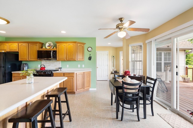 9050 Hartley Rd, Hallsville, MO 65255 - kitchen featuring black appliances, light countertops, a kitchen bar, ceiling fan, and tasteful backsplash