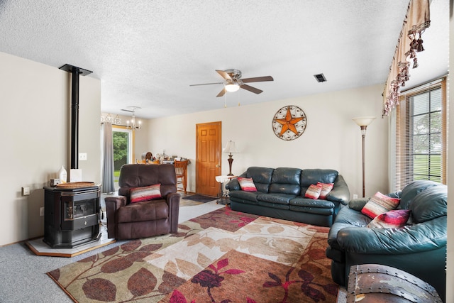 7275 N Route E, Columbia, MO 65202 - carpeted living area featuring a wood stove, a ceiling fan, a chandelier, and a textured ceiling