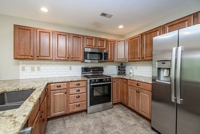 4504 Orrine St, Columbia, MO 65201 - kitchen featuring appliances with stainless steel finishes, backsplash, light stone countertops, brown cabinetry, and recessed lighting
