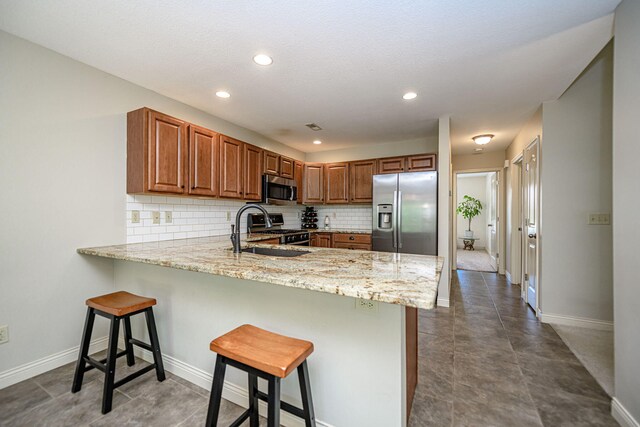 4504 Orrine St, Columbia, MO 65201 - kitchen featuring appliances with stainless steel finishes, a peninsula, a kitchen breakfast bar, backsplash, and recessed lighting