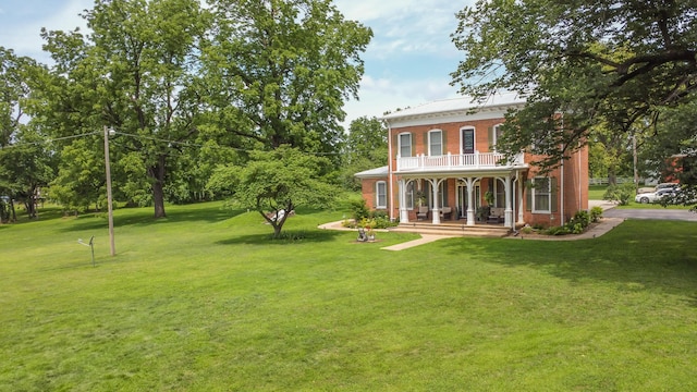 1001 Randolph St, Glasgow, MO 65254 - back of house with covered porch, brick siding, a balcony, and a lawn