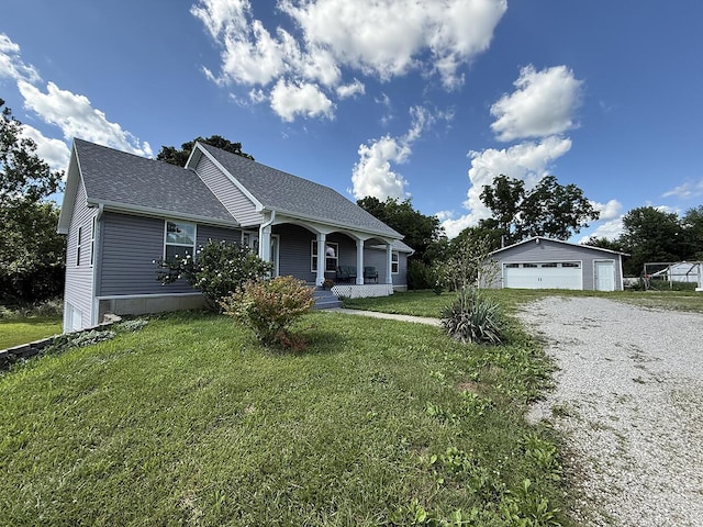3045 State Rd, Aa, Holts Summit, MO 65043 - view of front of property featuring covered porch, a detached garage, an outbuilding, a front lawn, and roof with shingles
