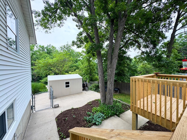 1000 Yale Dr, Columbia, MO 65203 - view of yard with a wooden deck, an outbuilding, a patio, view of wooded area, and a gate
