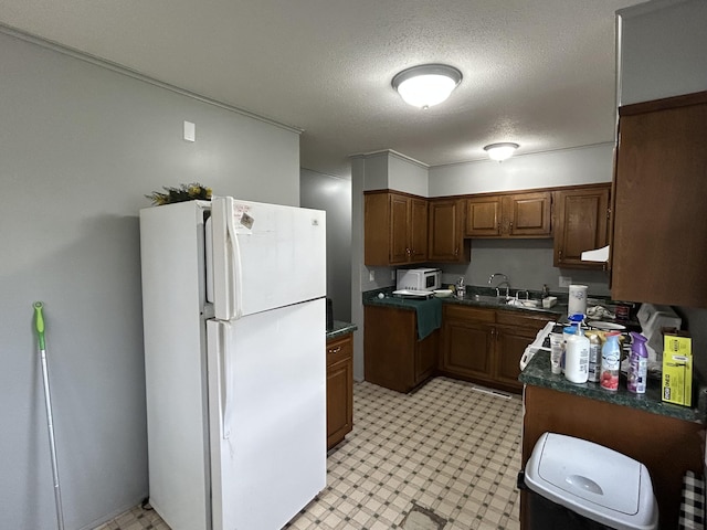 6009 E Eric Ln, Columbia, MO 65202 - kitchen featuring freestanding refrigerator, light floors, dark countertops, a textured ceiling, and brown cabinets