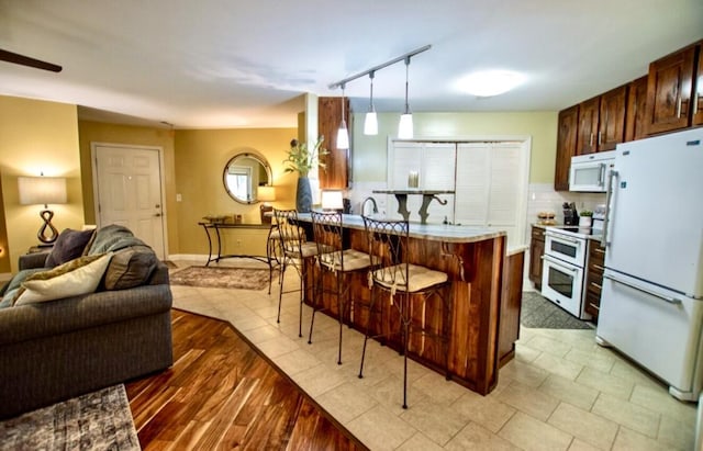 1902 Park Deville Pl, Columbia, MO 65203 - kitchen featuring white appliances, open floor plan, a breakfast bar, tasteful backsplash, and rail lighting