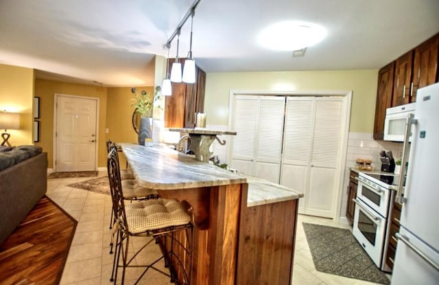 1902 Park Deville Pl, Columbia, MO 65203 - kitchen with white appliances, a peninsula, a kitchen breakfast bar, light countertops, and backsplash