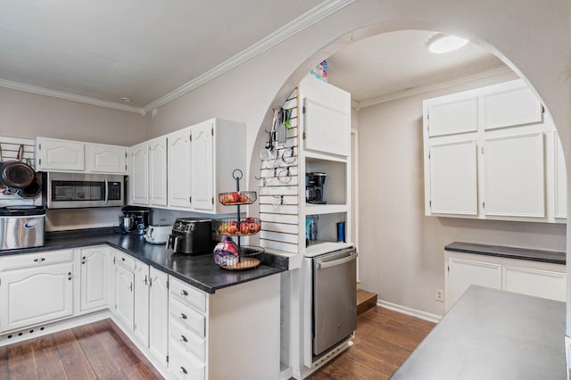 704 N Jefferson St, Mexico, MO 65265 - kitchen featuring stainless steel microwave, arched walkways, dark wood-style flooring, white cabinets, and dark countertops