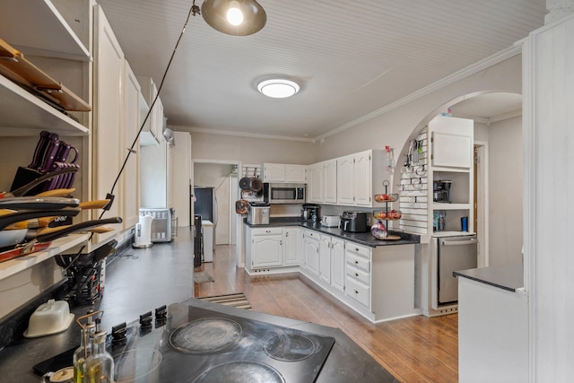 704 N Jefferson St, Mexico, MO 65265 - kitchen featuring arched walkways, stainless steel appliances, dark countertops, light wood-style flooring, and white cabinetry