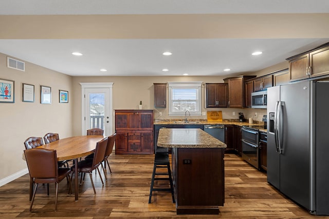 4969 W Red Tail Dr, Ashland, MO 65010 - kitchen featuring appliances with stainless steel finishes, dark brown cabinetry, a kitchen island, a kitchen breakfast bar, and dark wood finished floors