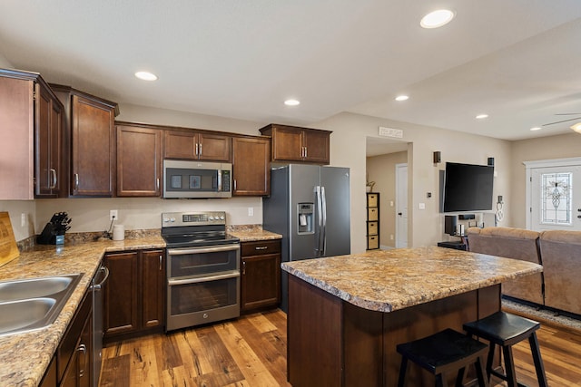 4969 W Red Tail Dr, Ashland, MO 65010 - kitchen featuring stainless steel appliances, open floor plan, wood finished floors, a breakfast bar area, and dark brown cabinetry