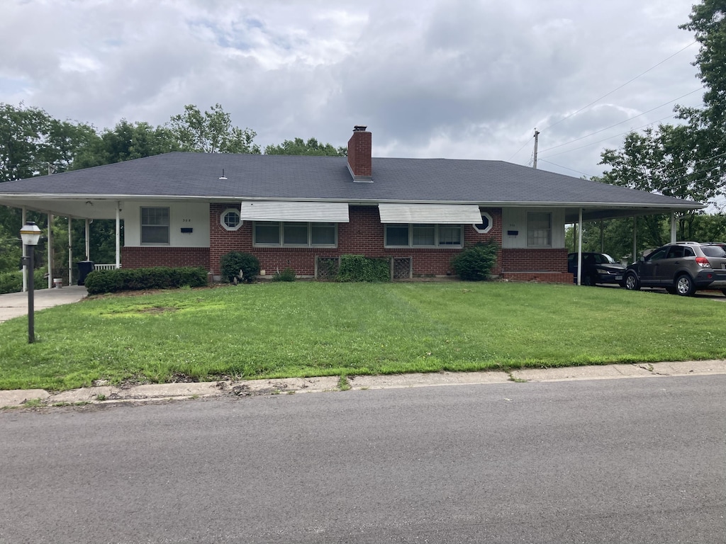 308-310 Loch Ln, Columbia, MO 65203 - view of front of house featuring an attached carport, brick siding, a front lawn, and a chimney