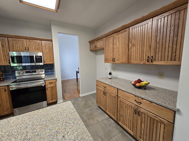 3109 Appalachian Dr, Columbia, MO 65203 - kitchen with appliances with stainless steel finishes, decorative backsplash, brown cabinetry, and light stone counters