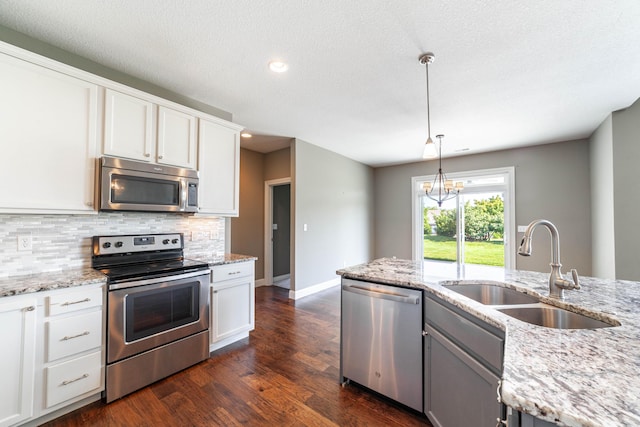 1915 Muirfield Dr, Columbia, MO 65203 - kitchen featuring appliances with stainless steel finishes, decorative backsplash, dark wood-type flooring, white cabinetry, and decorative light fixtures