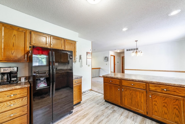6002 E Molly Ln, Columbia, MO 65202 - kitchen with black fridge, brown cabinets, light wood-style floors, a textured ceiling, and hanging light fixtures