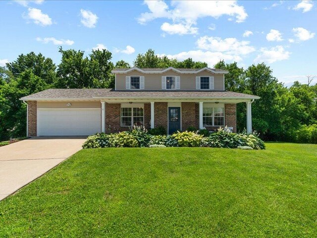 205 Johnson Ct, Ashland, MO 65010 - view of front facade with an attached garage, brick siding, concrete driveway, and a front yard