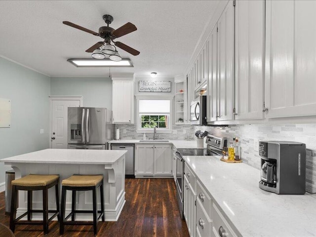 205 Johnson Ct, Ashland, MO 65010 - kitchen with stainless steel appliances, a ceiling fan, a breakfast bar, backsplash, and a kitchen island