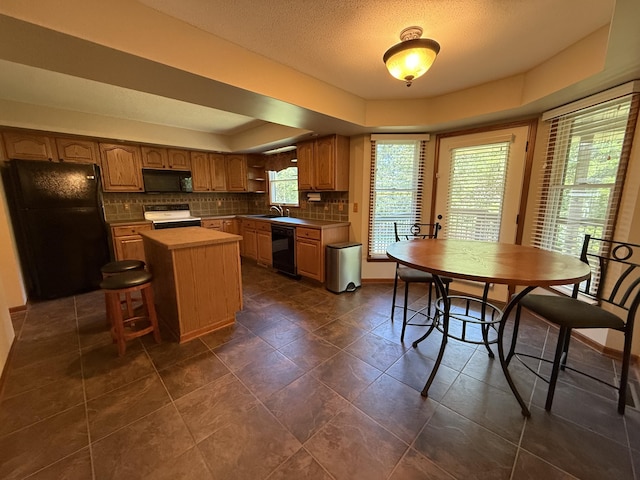 4413 Shoram Ct, Columbia, MO 65203 - kitchen featuring black appliances, decorative backsplash, a center island, a raised ceiling, and a textured ceiling