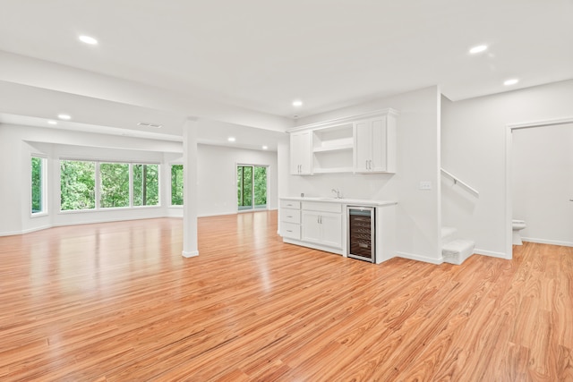 3348 S Old Ridge Rd, Columbia, MO 65203 - unfurnished living room featuring beverage cooler, bar with sink, recessed lighting, and light wood-style flooring