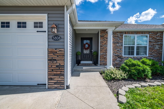 5808 Islip Dr, Columbia, MO 65201 - view of exterior entry featuring a garage, stone siding, and a shingled roof