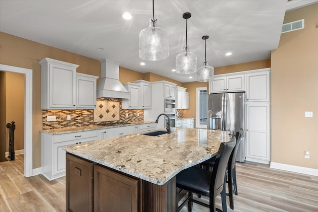 6406 Crooked Switch Ct, Columbia, MO 65201 - kitchen featuring custom exhaust hood, stainless steel appliances, light wood finished floors, decorative backsplash, and a large island