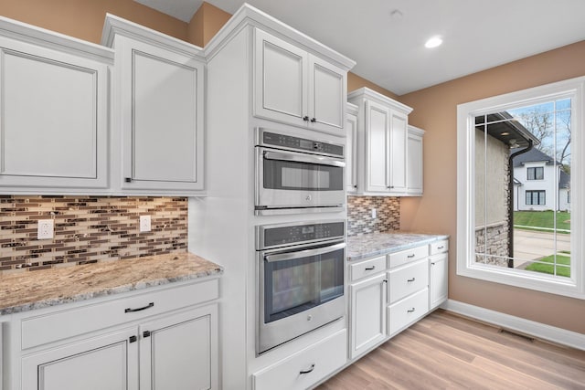 6406 Crooked Switch Ct, Columbia, MO 65201 - kitchen featuring stainless steel double oven, backsplash, white cabinetry, light wood-style flooring, and light stone countertops