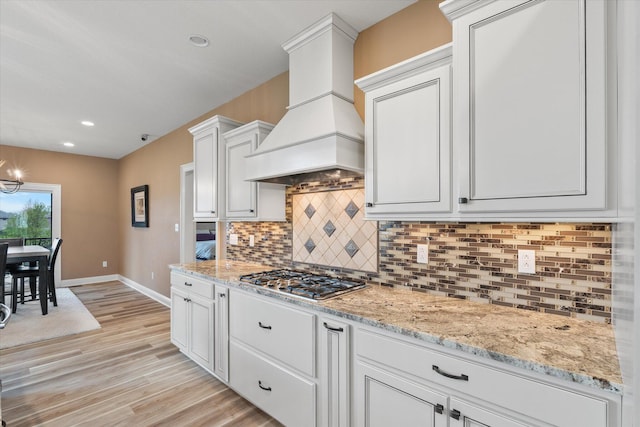 6406 Crooked Switch Ct, Columbia, MO 65201 - kitchen with premium range hood, stainless steel gas stovetop, tasteful backsplash, white cabinets, and light stone countertops