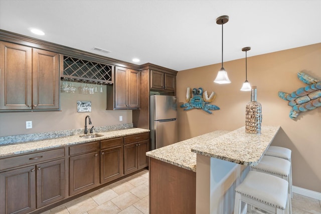 6406 Crooked Switch Ct, Columbia, MO 65201 - kitchen with freestanding refrigerator, a breakfast bar, decorative light fixtures, light stone counters, and a peninsula