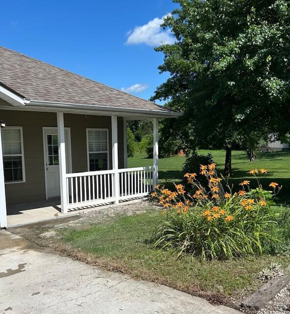 9855 N Route E, Harrisburg, MO 65256 - view of home's exterior featuring a shingled roof, covered porch, and a lawn