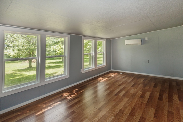 9855 N Route E, Harrisburg, MO 65256 - unfurnished room featuring a wall mounted air conditioner, dark wood-style floors, a textured ceiling, and plenty of natural light