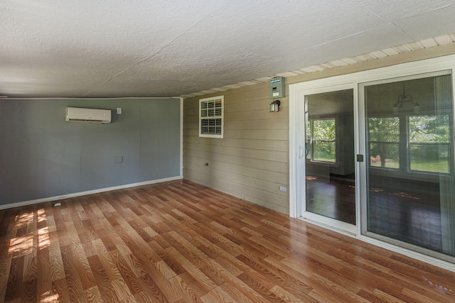 9855 N Route E, Harrisburg, MO 65256 - spare room with an AC wall unit, wood finished floors, a textured ceiling, and wooden walls