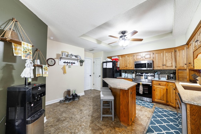 605 Teakwood Ct, Ashland, MO 65010 - kitchen with appliances with stainless steel finishes, a center island, backsplash, ceiling fan, and a raised ceiling