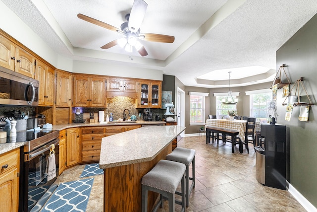 605 Teakwood Ct, Ashland, MO 65010 - kitchen featuring stainless steel appliances, a tray ceiling, tasteful backsplash, a breakfast bar, and a center island