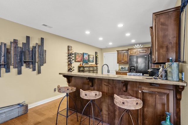 3509 Tuscany, Columbia, MO 65202 - kitchen featuring black refrigerator with ice dispenser, light countertops, light wood-type flooring, recessed lighting, and a kitchen bar