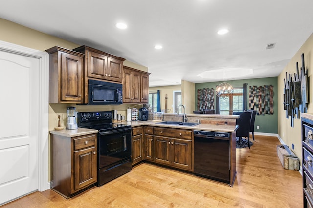 3509 Tuscany, Columbia, MO 65202 - kitchen with black appliances, a peninsula, light countertops, a chandelier, and light wood finished floors