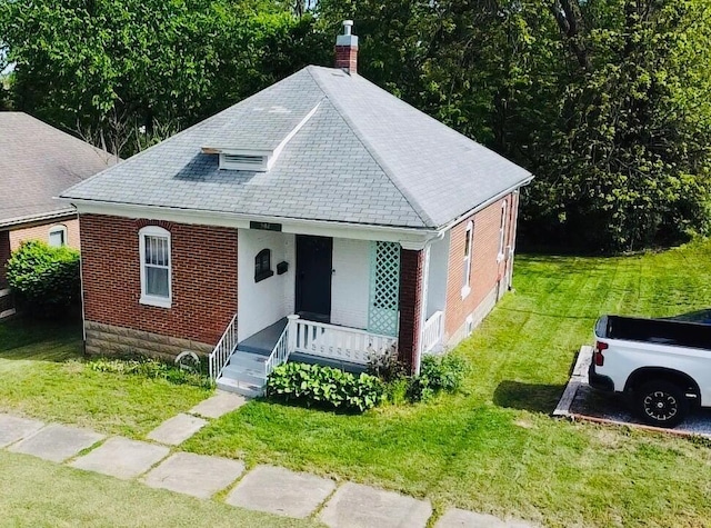 902 E Morgan St, Boonville, MO 65233 - view of front of home with covered porch, a front lawn, a chimney, and brick siding