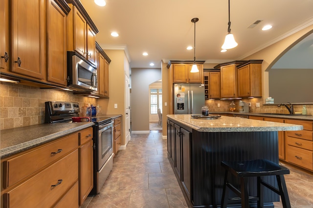 315 W Proctor St, Sturgeon, MO 65284 - kitchen featuring stainless steel appliances, brown cabinetry, arched walkways, a center island, and crown molding