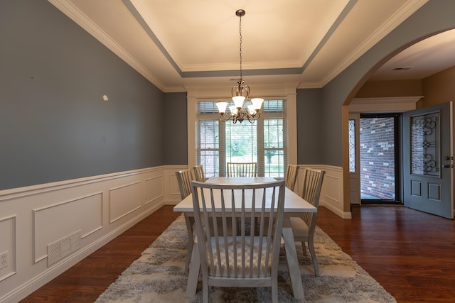 315 W Proctor St, Sturgeon, MO 65284 - dining area featuring a tray ceiling, a decorative wall, dark wood-type flooring, arched walkways, and wainscoting