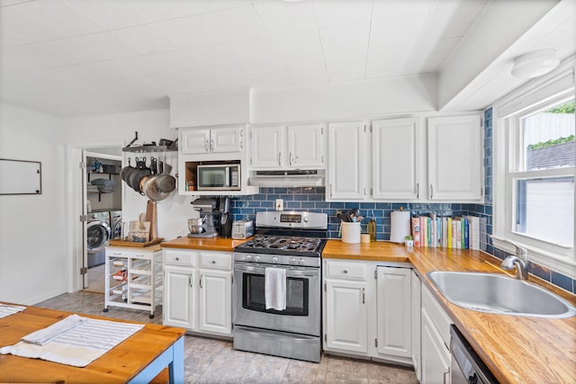 708 Clayton St, Columbia, MO 65203 - kitchen featuring appliances with stainless steel finishes, separate washer and dryer, under cabinet range hood, butcher block counters, and backsplash