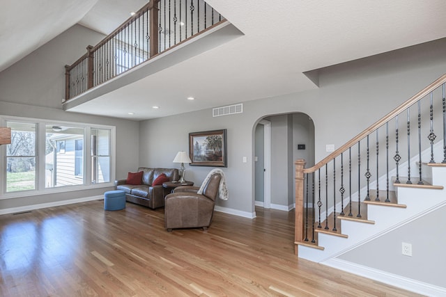 8900 W Graham Rd, Rocheport, MO 65279 - living room featuring arched walkways, wood finished floors, stairs, recessed lighting, and a towering ceiling