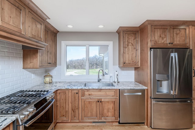 8900 W Graham Rd, Rocheport, MO 65279 - kitchen featuring appliances with stainless steel finishes, light stone counters, decorative backsplash, light wood-type flooring, and brown cabinets