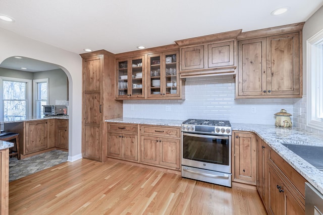 8900 W Graham Rd, Rocheport, MO 65279 - kitchen with appliances with stainless steel finishes, arched walkways, light wood-type flooring, light stone countertops, and brown cabinets