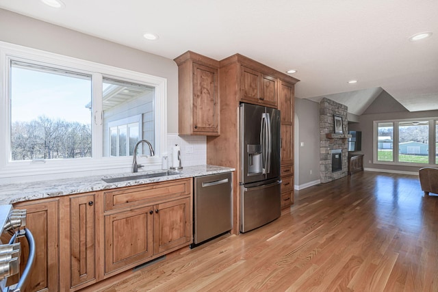 8900 W Graham Rd, Rocheport, MO 65279 - kitchen with stainless steel appliances, a stone fireplace, light wood-style floors, brown cabinets, and light stone countertops