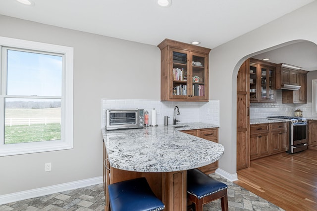 8900 W Graham Rd, Rocheport, MO 65279 - kitchen with stainless steel range with gas cooktop, arched walkways, a peninsula, a breakfast bar area, and backsplash