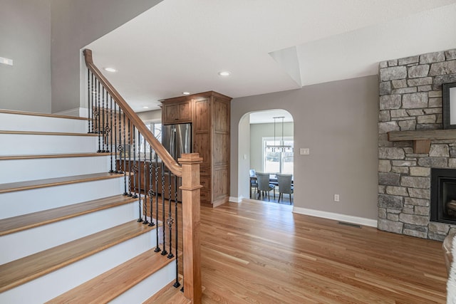 8900 W Graham Rd, Rocheport, MO 65279 - staircase featuring arched walkways, wood finished floors, a stone fireplace, and recessed lighting
