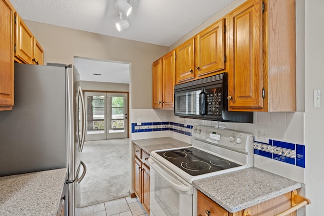 2002 Chapel Hill Rd, Columbia, MO 65203 - kitchen with electric range, freestanding refrigerator, black microwave, light countertops, and light tile patterned floors