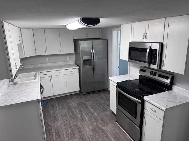 809 S 4th St, Moberly, MO 65259 - kitchen featuring appliances with stainless steel finishes, dark wood-type flooring, light countertops, a textured ceiling, and white cabinets