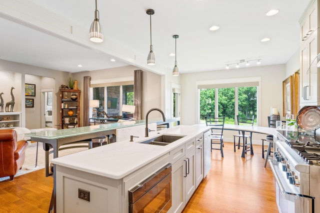 1107 Marcassin Dr, Columbia, MO 65201 - kitchen with gas range oven, stainless steel microwave, an island with sink, white cabinets, and light wood-style floors