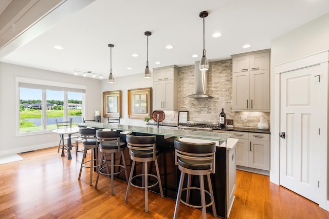 1107 Marcassin Dr, Columbia, MO 65201 - kitchen featuring wall chimney exhaust hood, decorative backsplash, a kitchen breakfast bar, light wood-style floors, and recessed lighting