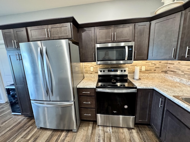 921 S Columbia St, Centralia, MO 65240 - kitchen with stainless steel appliances, wood finished floors, dark brown cabinetry, backsplash, and light stone counters
