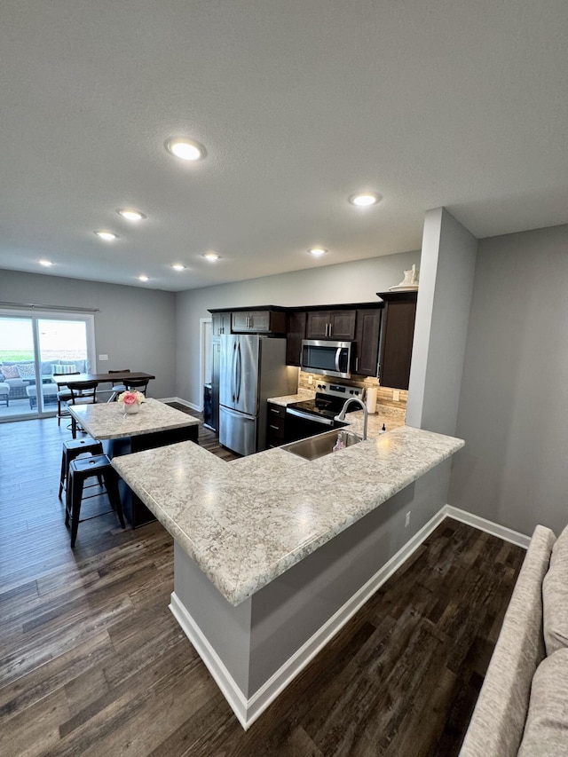 921 S Columbia St, Centralia, MO 65240 - kitchen with appliances with stainless steel finishes, dark wood-type flooring, a peninsula, recessed lighting, and dark brown cabinets